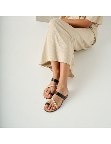 Sandalo greco in pelle Mykonos nero, modella seduta a terra appoggiata a un cubo di marmo, vista prospettica, piano me - MONPIEL Sandalo greco in pelle Mykonos nero, modella seduta a terra appoggiata a un cubo di marmo, vista prospettica, piano me - MONPIEL