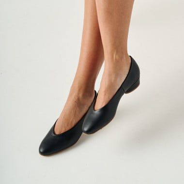 Bailarina com salto na cor preta, plano de pernas cruzadas com fundo branco - MONPIEL