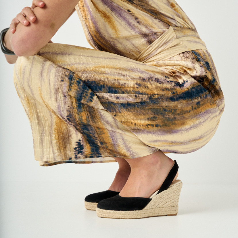 Black suede wedge leather espadrille, side view, model crouching, close-up of wedges - MONPIEL