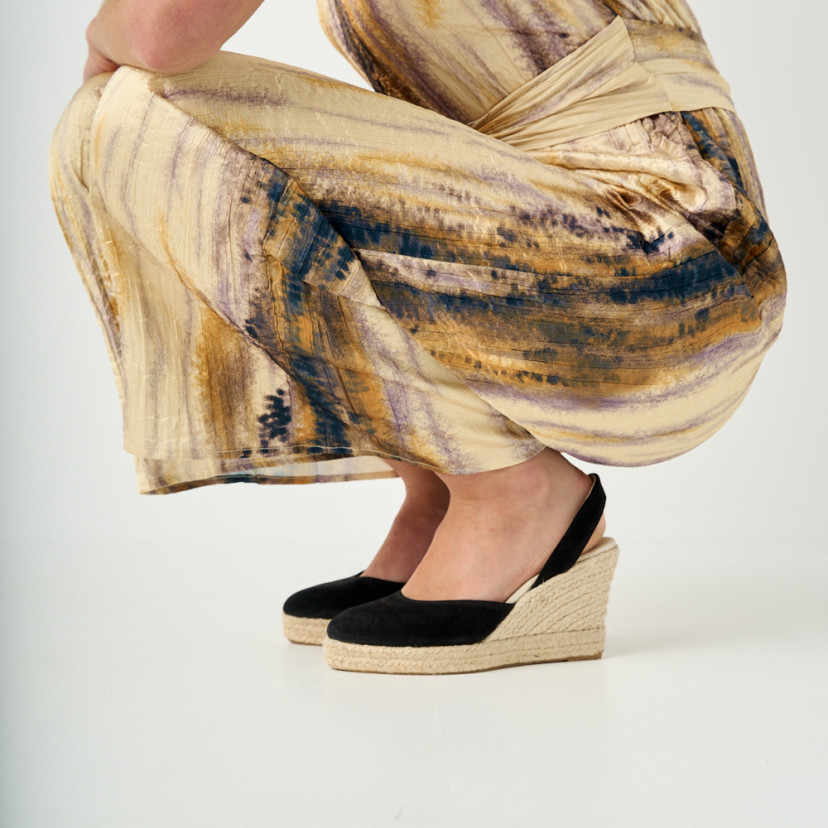 Black suede wedge leather espadrille, side view, model crouching, close-up of wedges - MONPIEL