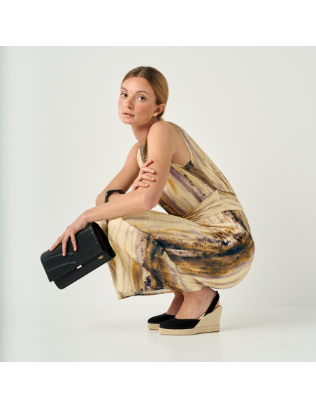 Schwarze Keil-Espadrille aus Wildleder, Weitwinkelaufnahme des hockenden Models mit Ledertasche in der Hand - MONPIEL