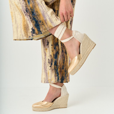 Espadrille à talon compensé Elba en cuir noir, jambes croisées avec un pied posé sur la table - MONPIEL 2