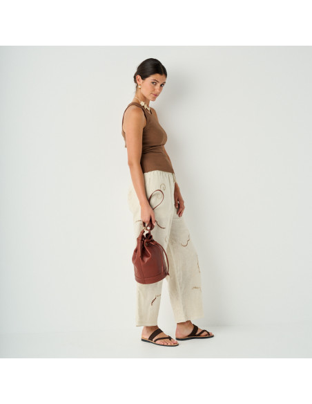 Kleiner Beuteltasche aus Leder in der Farbe Cognac, in der Hand gehalten, Weitwinkelaufnahme des stehenden Models - MONPIEL