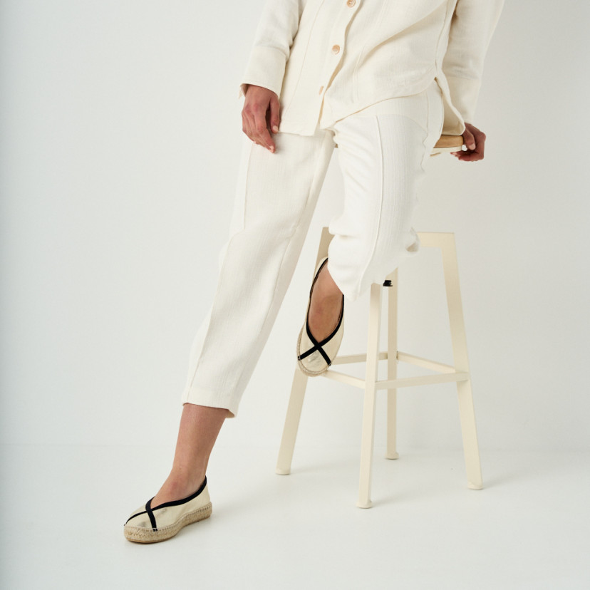 Gaia platinum ballerina espadrille with perspective and front view, mid shot with foot resting on stool - MONPIEL