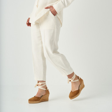 Espadrille à talon compensé Elba en cuir noir, jambes croisées avec un pied posé sur la table - MONPIEL 2