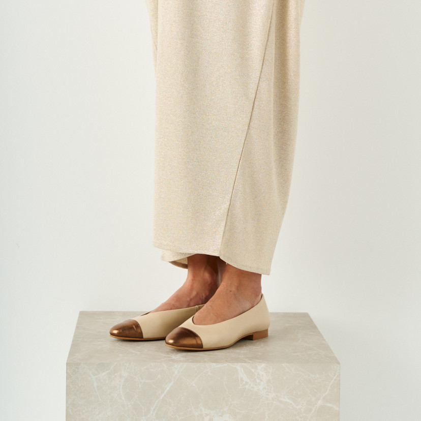 Ameliè flat ballerina with metallic beige/copper toe, perspective view, model standing on marble cube, mid shot - MONPIEL