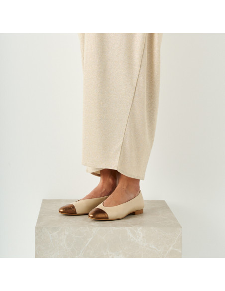 Ameliè flat ballerina with metallic beige/copper toe, perspective view, model standing on marble cube, mid shot - MONPIEL Ameliè flat ballerina with metallic beige/copper toe, perspective view, model standing on marble cube, mid shot - MONPIEL