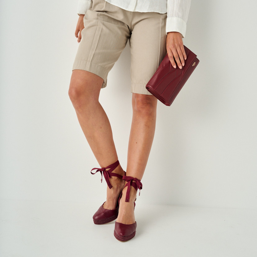 Creta burgundy leather wedge espadrille, mid shot with leather handbag in hand - MONPIEL