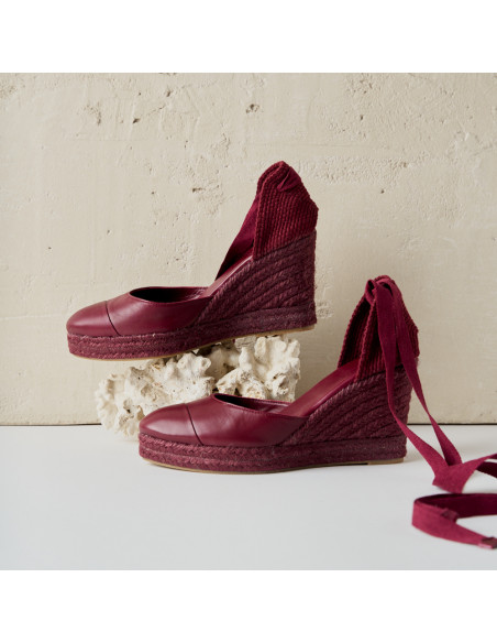 Creta burgundy leather wedge espadrille, close-up with side view, wall background - MONPIEL Creta burgundy leather wedge espadrille, close-up with side view, wall background - MONPIEL