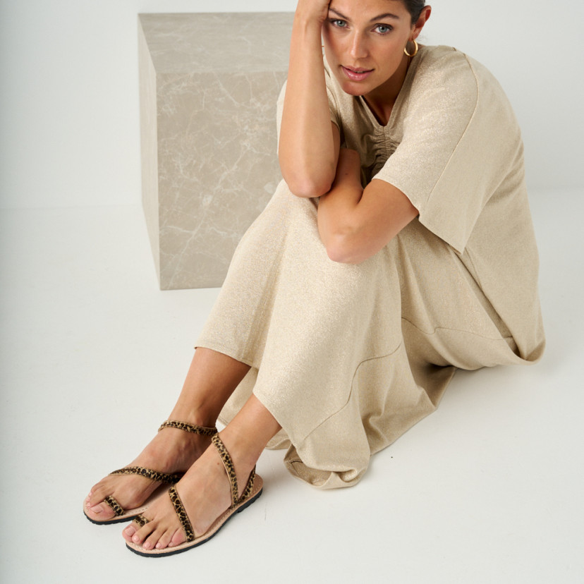 Animal print leather Milos strap sandals with perspective view and full-length shot of the model sitting on the floor - MONPIEL