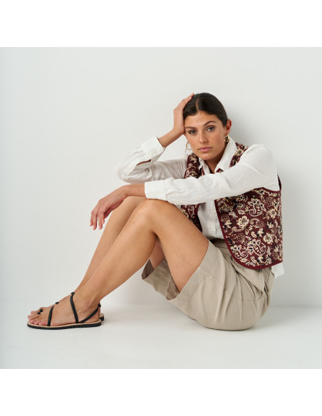 Black braided sandal Milos with side view, wide shot of model sitting on the floor - MONPIEL