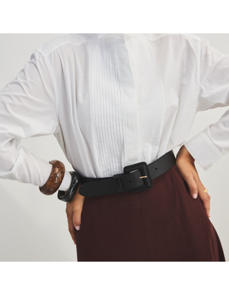 Wide black leather women's belt with covered buckle on burgundy skirt and white shirt, front view - MONPIEL Wide black leather women's belt with covered buckle on burgundy skirt and white shirt, front view - MONPIEL