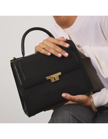 Petit sac en cuir pour femme années 60 en noir avec vue de face, tenu à deux mains en gros plan - MONPIEL