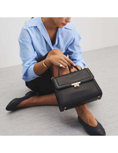 Bolsa de couro feminina anos 60 na cor preta apoiada na perna com detalhe de bailarinas - MONPIEL