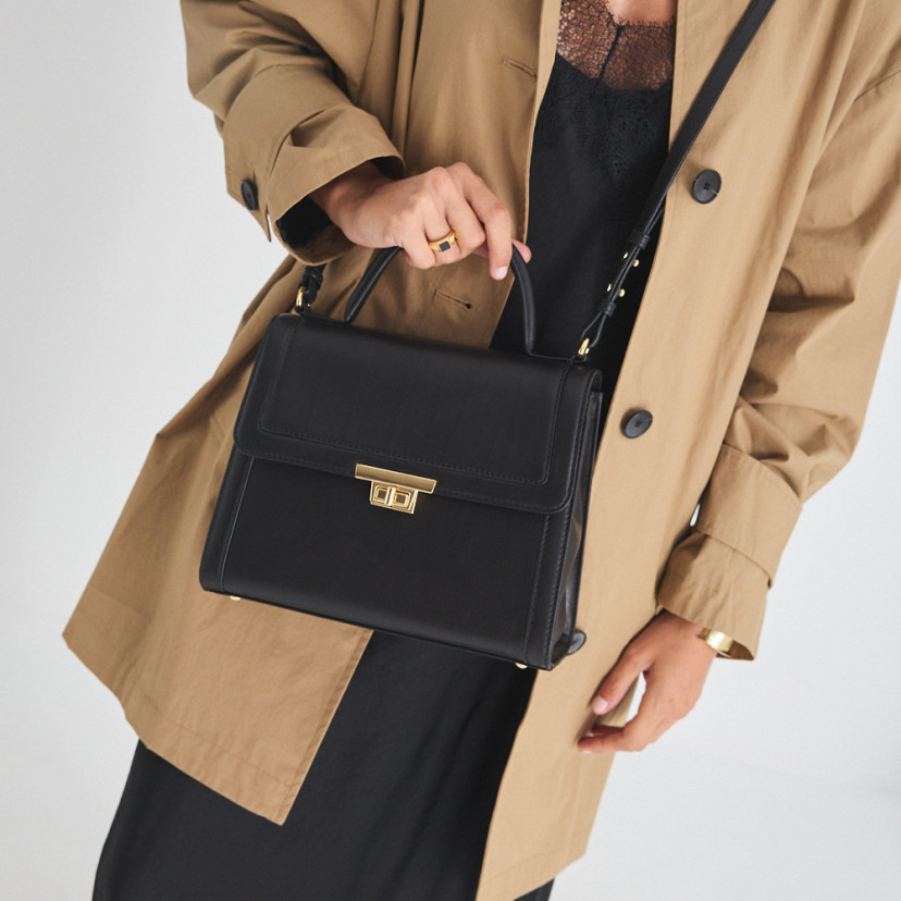 Bolsa de couro feminina anos 60 na cor preta usada a tiracolo, segurada pela alça curta - MONPIEL