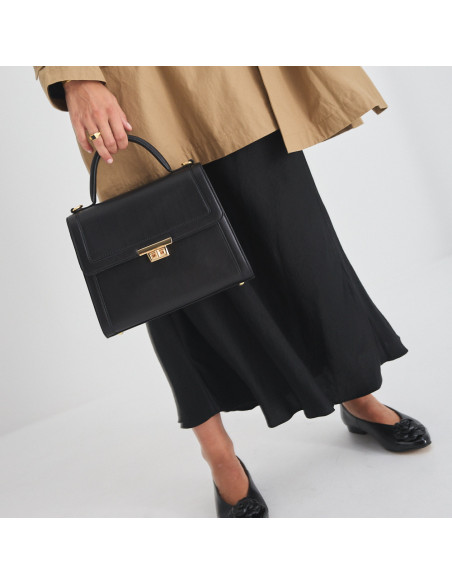 Borsa da donna in pelle anni '60 nera con vista frontale, tenuta dal manico corto, abbinata a ballerine con dettaglio - MONPIEL