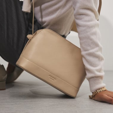 Mittlere Ledertasche in Lederfarbe, Frontalansicht, geneigt, auf einer Vase ruhend - MONPIEL 2