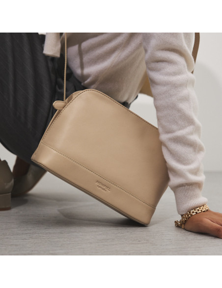 Bolsa média de couro na cor bege inclinada, apoiada no chão - MONPIEL Bolsa média de couro na cor bege inclinada, apoiada no chão - MONPIEL