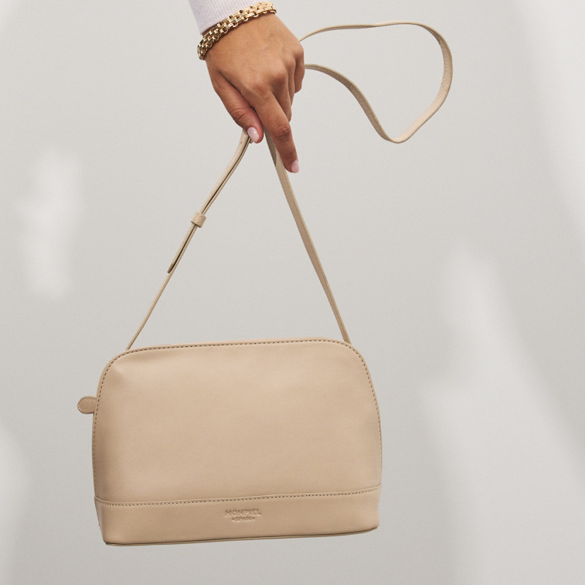 Bolsa média de couro na cor bege com vista frontal, pendurada na mão - MONPIEL