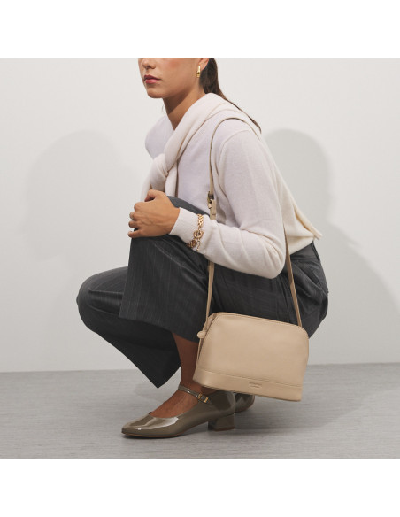 Bolsa média de couro na cor bege pendurada no ombro, modelo agachada - MONPIEL Bolsa média de couro na cor bege pendurada no ombro, modelo agachada - MONPIEL