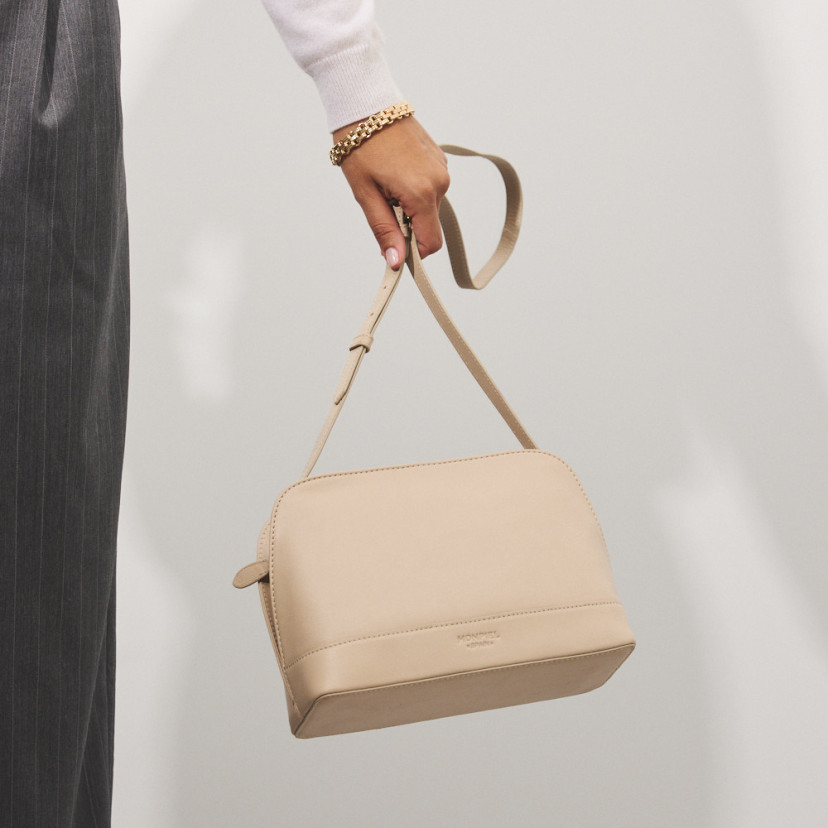 Bolsa média de couro na cor bege com vista frontal, pendurada na mão - MONPIEL