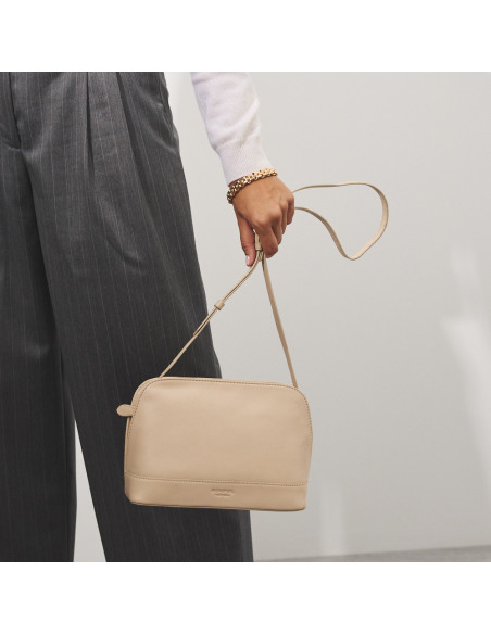 Bolsa média de couro na cor bege com vista frontal, pendurada na mão em movimento - MONPIEL Bolsa média de couro na cor bege com vista frontal, pendurada na mão em movimento - MONPIEL