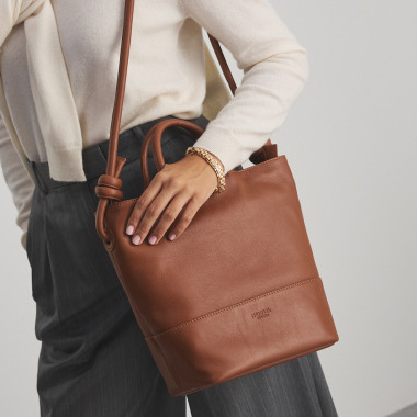 Bolsa grande com nós de couro na cor couro com vista frontal, alça curta segurada na mão - MONPIEL 2