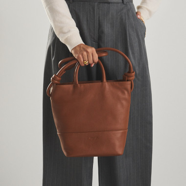 Bolsa grande com nós de couro na cor couro com vista frontal, alça curta segurada na mão - MONPIEL 2