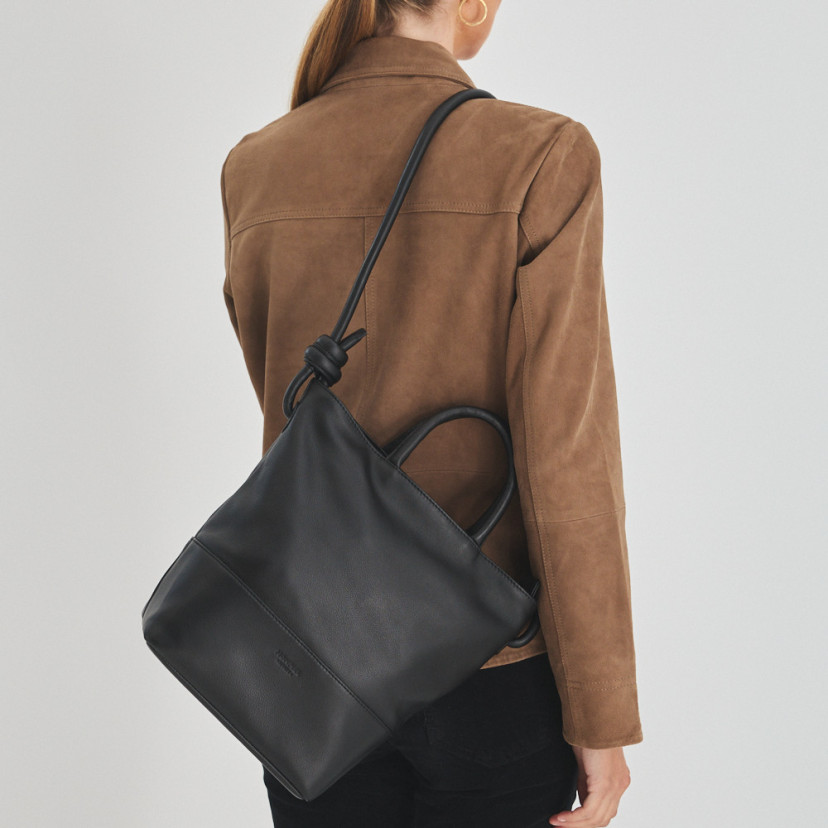 Bolsa grande com nós de couro na cor preta pendurada no ombro, costas da modelo - MONPIEL
