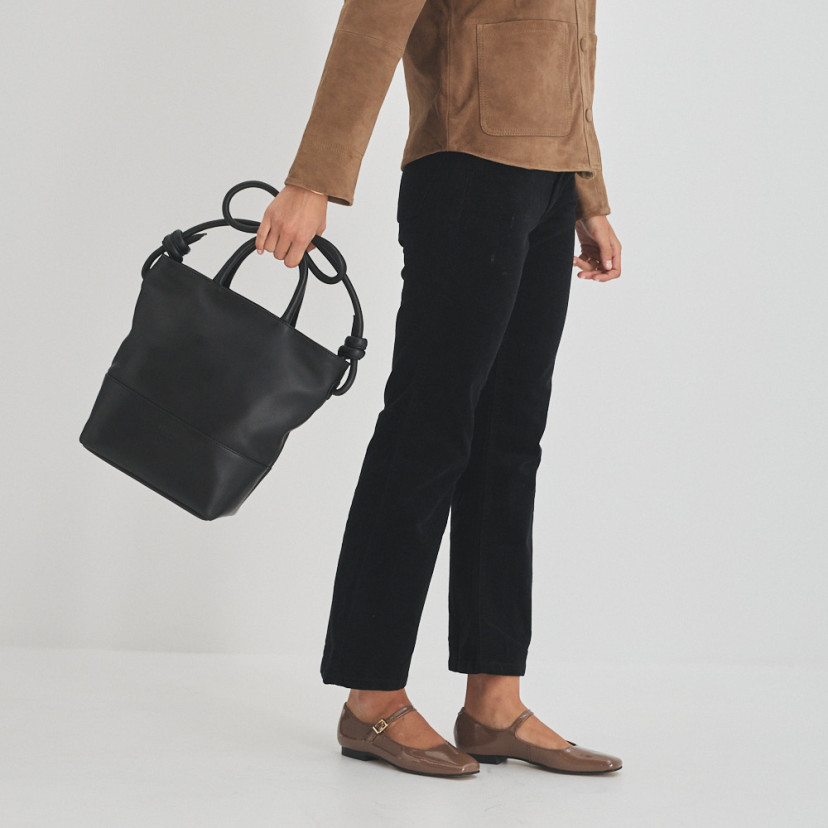 Bolsa grande com nós de couro na cor preta segurando as alças curtas, bolsa em movimento - MONPIEL