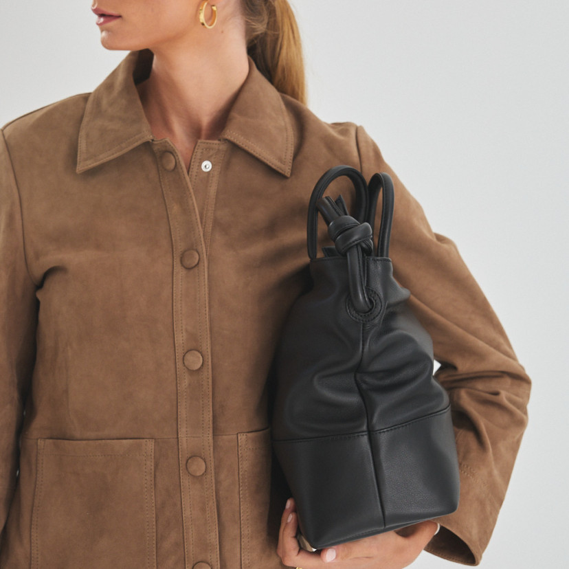 Bolsa grande com nós de couro na cor preta com modelo segurando a bolsa debaixo do braço - MONPIEL