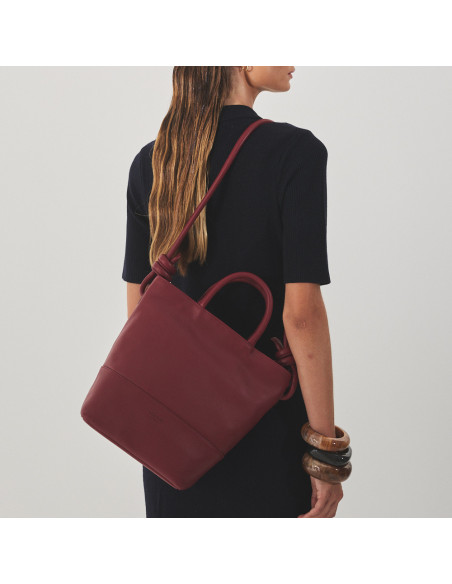 Large burgundy leather knot handbag hanging from the shoulder with the model carrying the bag on the back - MONPIEL Large burgundy leather knot handbag hanging from the shoulder with the model carrying the bag on the back - MONPIEL