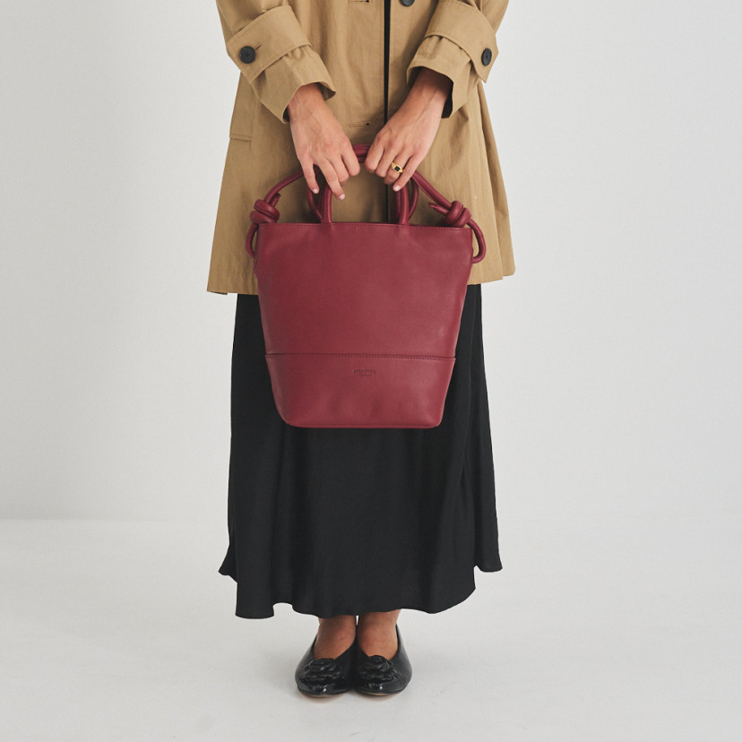 Grande bolsa de couro com nós na cor bordô, vista frontal segurando as alças curtas - MONPIEL