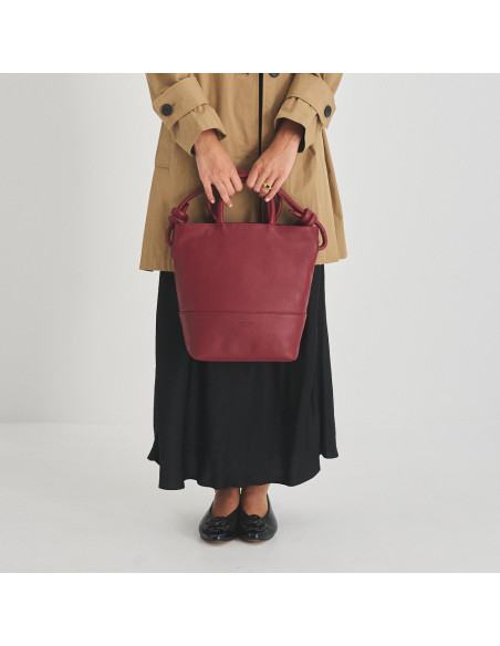 Large leather knotted bag in burgundy, front view holding short handles - MONPIEL Large leather knotted bag in burgundy, front view holding short handles - MONPIEL