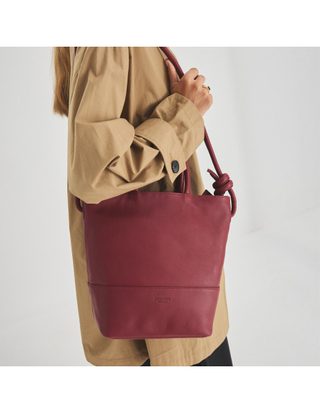 Grand sac en cuir avec des nœuds de couleur bordeaux, suspendu à l'épaule avec le modèle en profil et vue avant du sac - MONPIEL