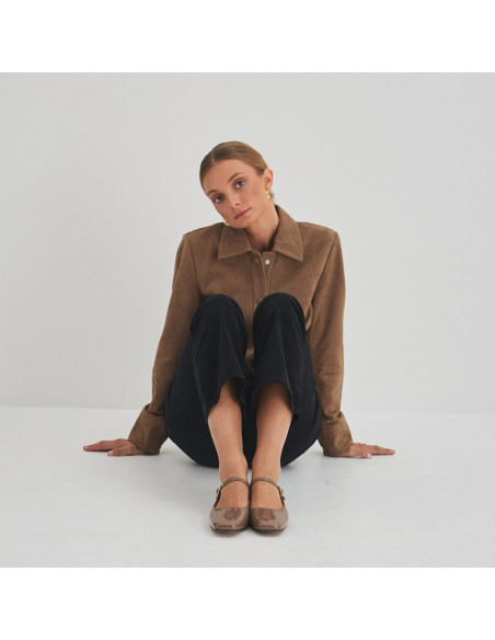 Cinnamon patent leather strap Mary Jane Carlota, front view, wide shot of model sitting on the floor - MONPIEL Cinnamon patent leather strap Mary Jane Carlota, front view, wide shot of model sitting on the floor - MONPIEL