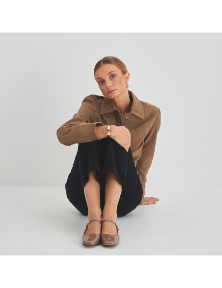 Cinnamon patent leather strap Mary Jane Carlota, front view, wide shot of model sitting on the floor - MONPIEL Cinnamon patent leather strap Mary Jane Carlota, front view, wide shot of model sitting on the floor - MONPIEL