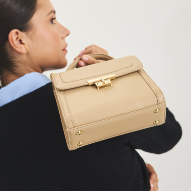 Kleine beige Ledertasche im 60er-Jahre-Stil für Damen, Frontalansicht, neben einer Blume - MONPIEL 2
