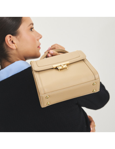 Bolsa de couro feminina pequena anos 60 na cor bege, vista em perspectiva, bolsa segurada no ombro - MONPIEL