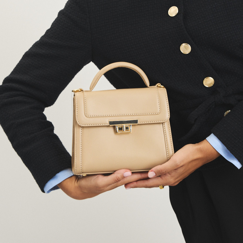 Small 60's leather handbag for women in beige, held in hands, front view - MONPIEL