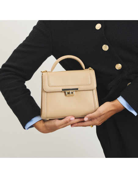 Bolsa de couro feminina pequena anos 60 na cor bege, apoiada nas mãos, vista frontal - MONPIEL