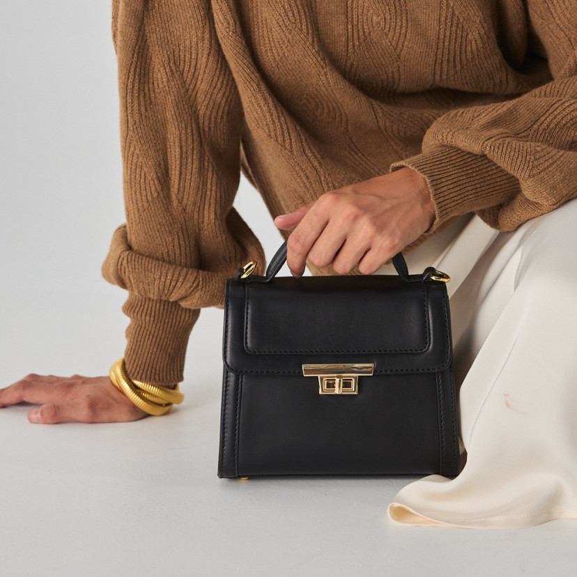 Bolsa de couro feminina pequena anos 60 na cor preta, vista frontal, apoiada no chão - MONPIEL