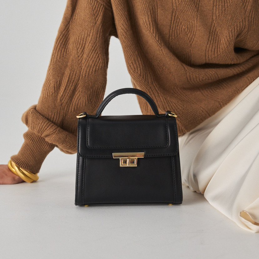 Bolsa de couro feminina pequena anos 60 na cor preta, vista frontal, apoiada no chão - MONPIEL