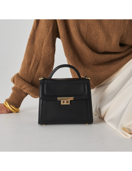 Small 60's leather handbag for women in black, front view, resting on the floor - MONPIEL