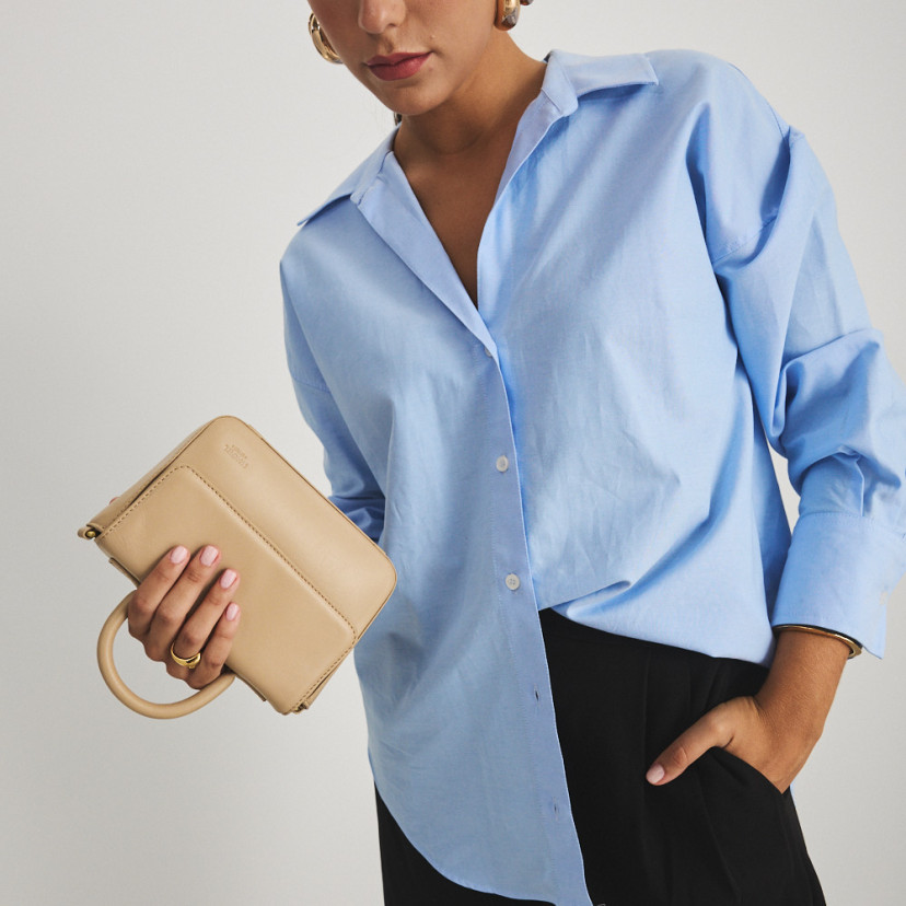 Small Armado leather handbag in beige, held upside down with the hand, mid shot - MONPIEL