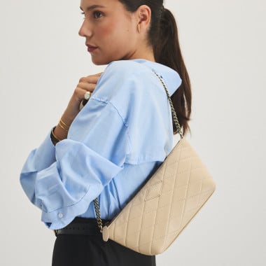 Small New York quilted leather handbag for women in beige, front view, worn over the shoulder at an angle - MONPIEL