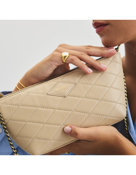 Small New York quilted leather handbag for women in beige, close-up between the hands - MONPIEL