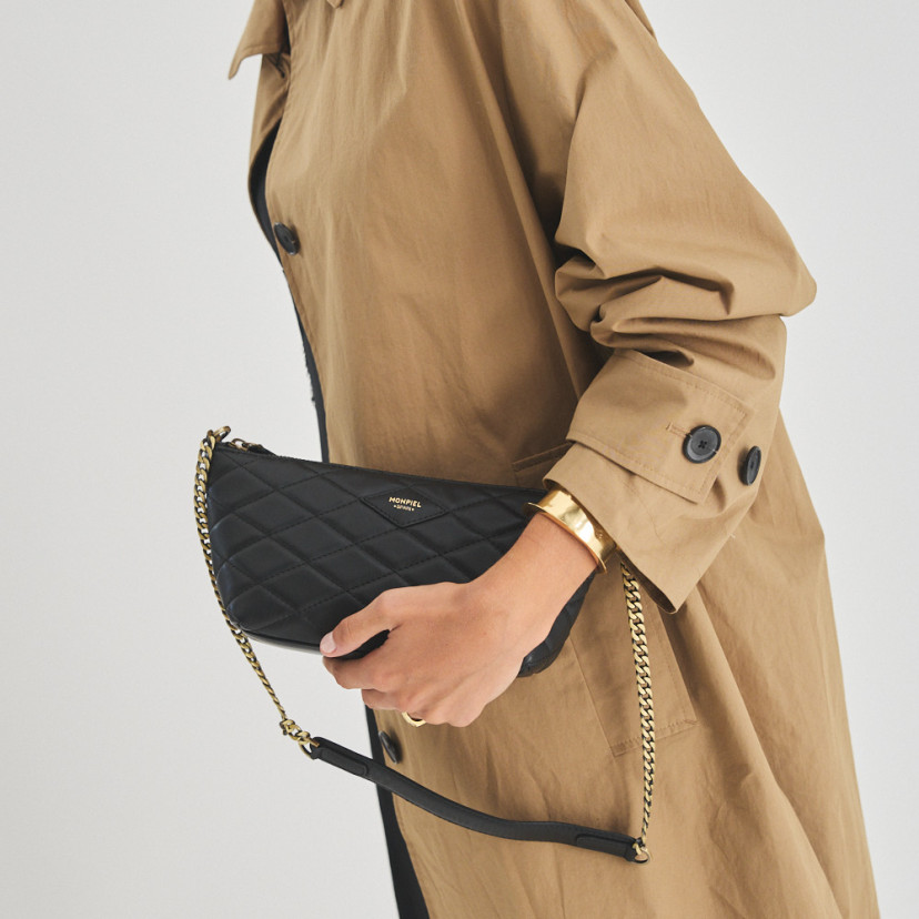 Bolsa de couro feminina pequena acolchoada New York na cor preta, vista frontal, segurada na mão - MONPIEL