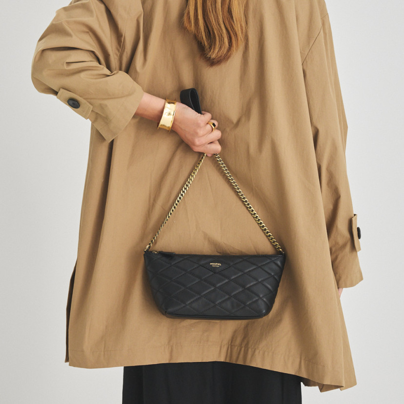 Bolsa de couro feminina pequena acolchoada New York na cor preta, vista frontal, segurada nas costas - MONPIEL