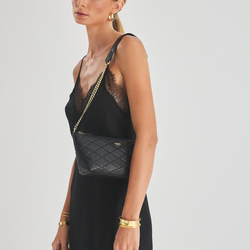 Small New York quilted leather handbag for women in black, worn over the shoulder, mid shot - MONPIEL